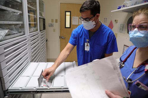 Registered nurse Lt. Kyle Costello, left, gets medication from the Omnicell, which houses and distributes patients’ medications, as Lawrence General’s Shauna Wade looks on. (U.S. Army photo by Spc. Daniel Thompson)